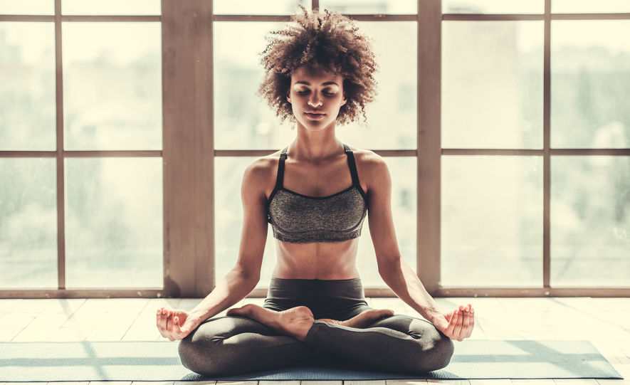 Attractive Afro American girl in sportswear is meditating while doing yoga